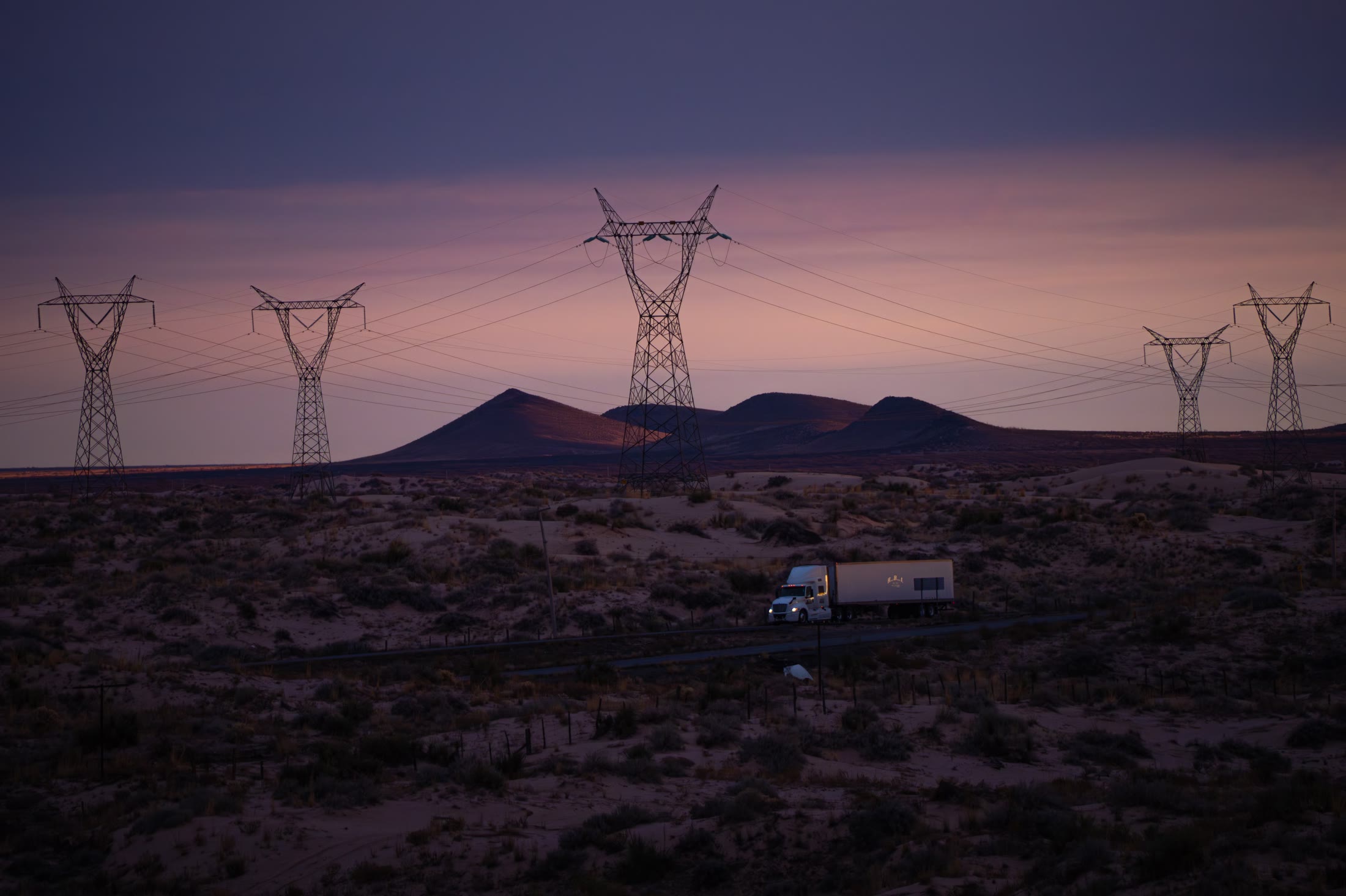 Long-haul commercial truck operating beneath an electrical transmission network
